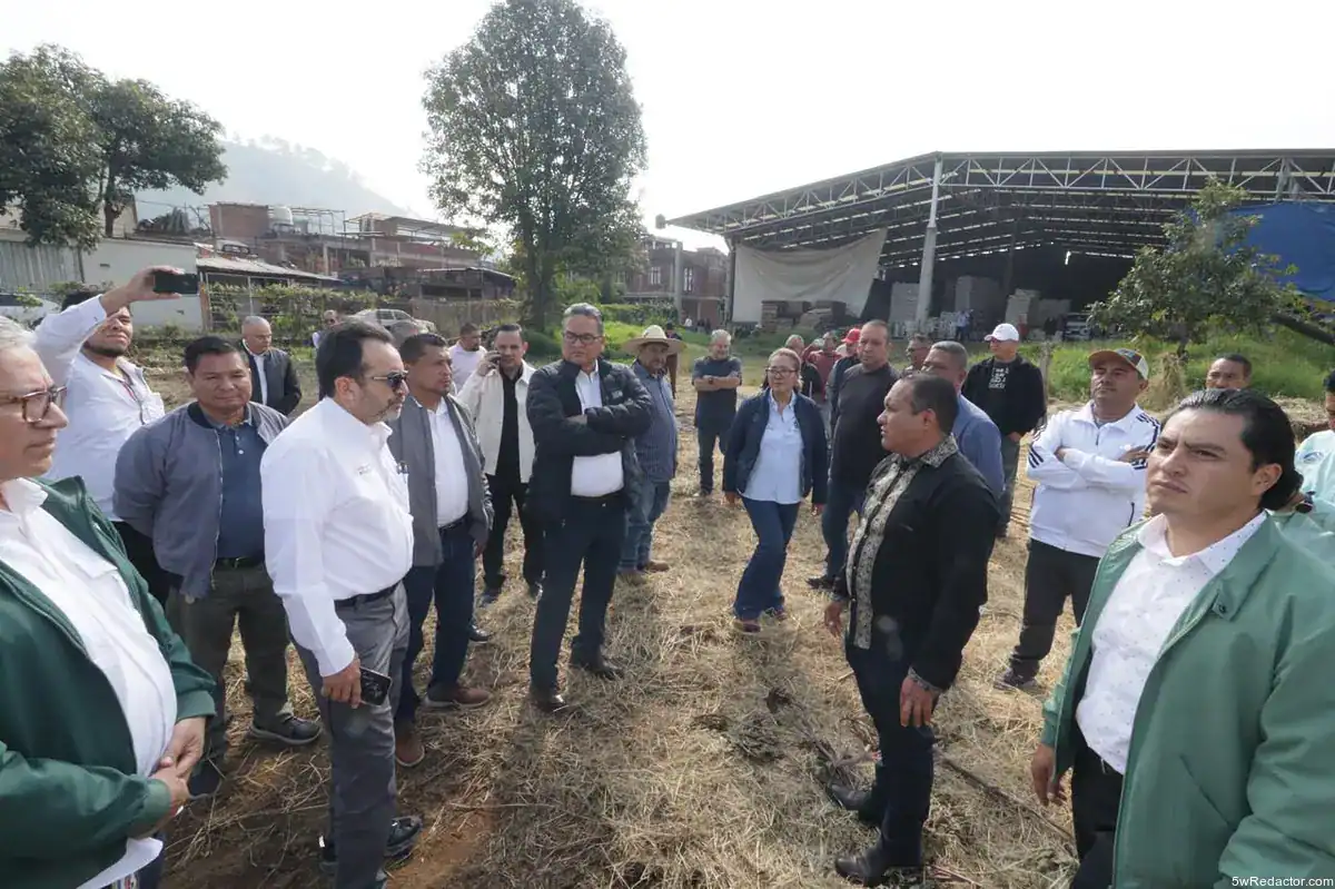 Reunión de autoridades en campo agrícola en un espacio abierto con estructura industrial al fondo.