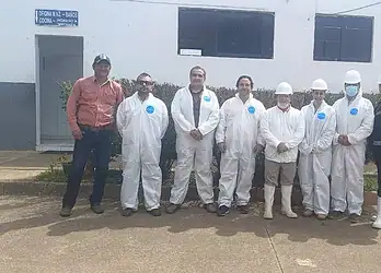 Personal de salud y construcción en exteriores, grupo con equipo de protección en entorno institucional.