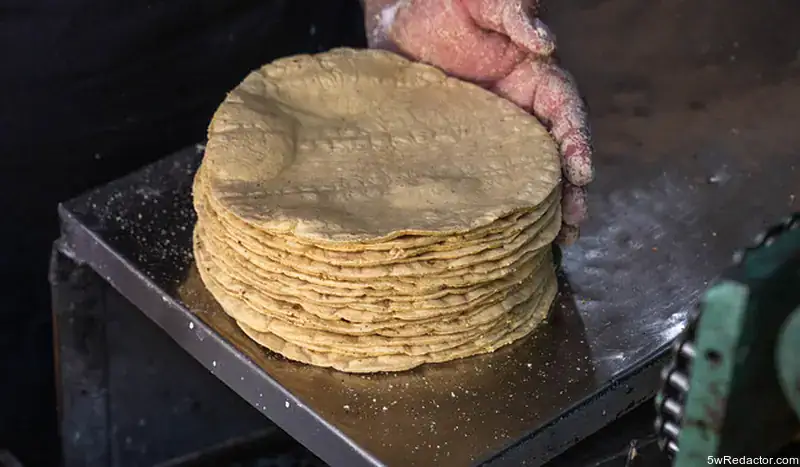 Tortillas de maíz tradicionales hechas a mano en proceso de cocción artesanal.
