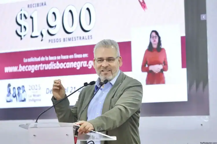 1. Hombre hablando en conferencia con pantalla de fondos de becas en segundo plano.