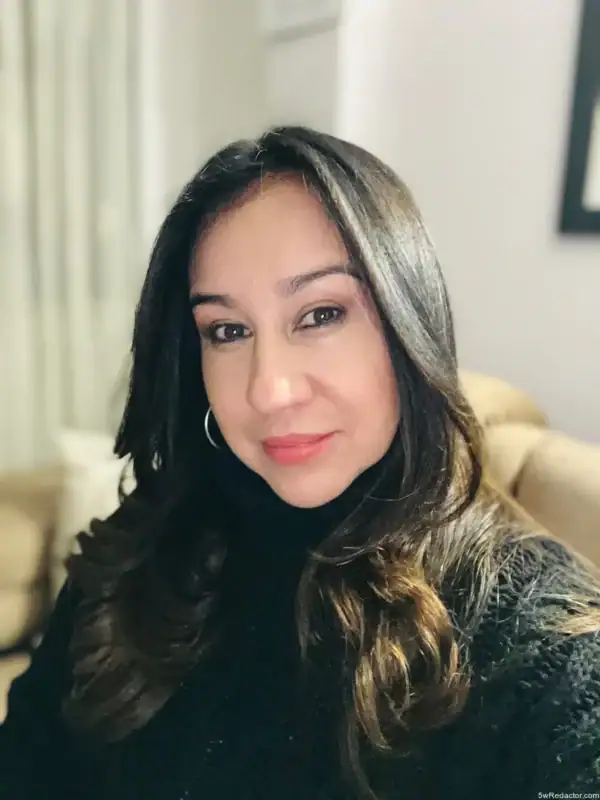 Rostro de mujer sonriendo, cabello largo y rizado, estilo natural, fondo de interiores, atractivo para contenido de belleza y estilo de vida.