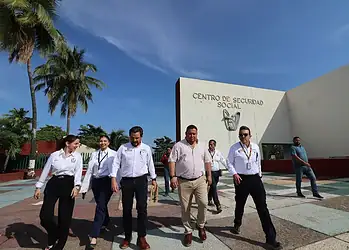 Seguridad social, personal en uniforme saliendo del centro de seguridad social en clima soleado.
